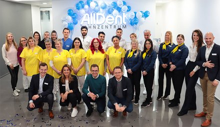 Teamfoto AllDent Zahnzentrum Karlsruhe. Im Hintergrund weiße und blaue Luftballons