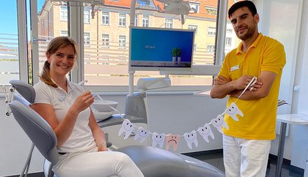Zahnärztin und Zahnarzt-Assistent halten eine Girlande mit Zähnen