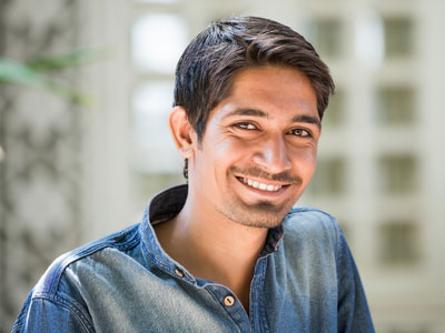 Schwarzhaariger Mann in Jeanshemd lächelt in Kamera